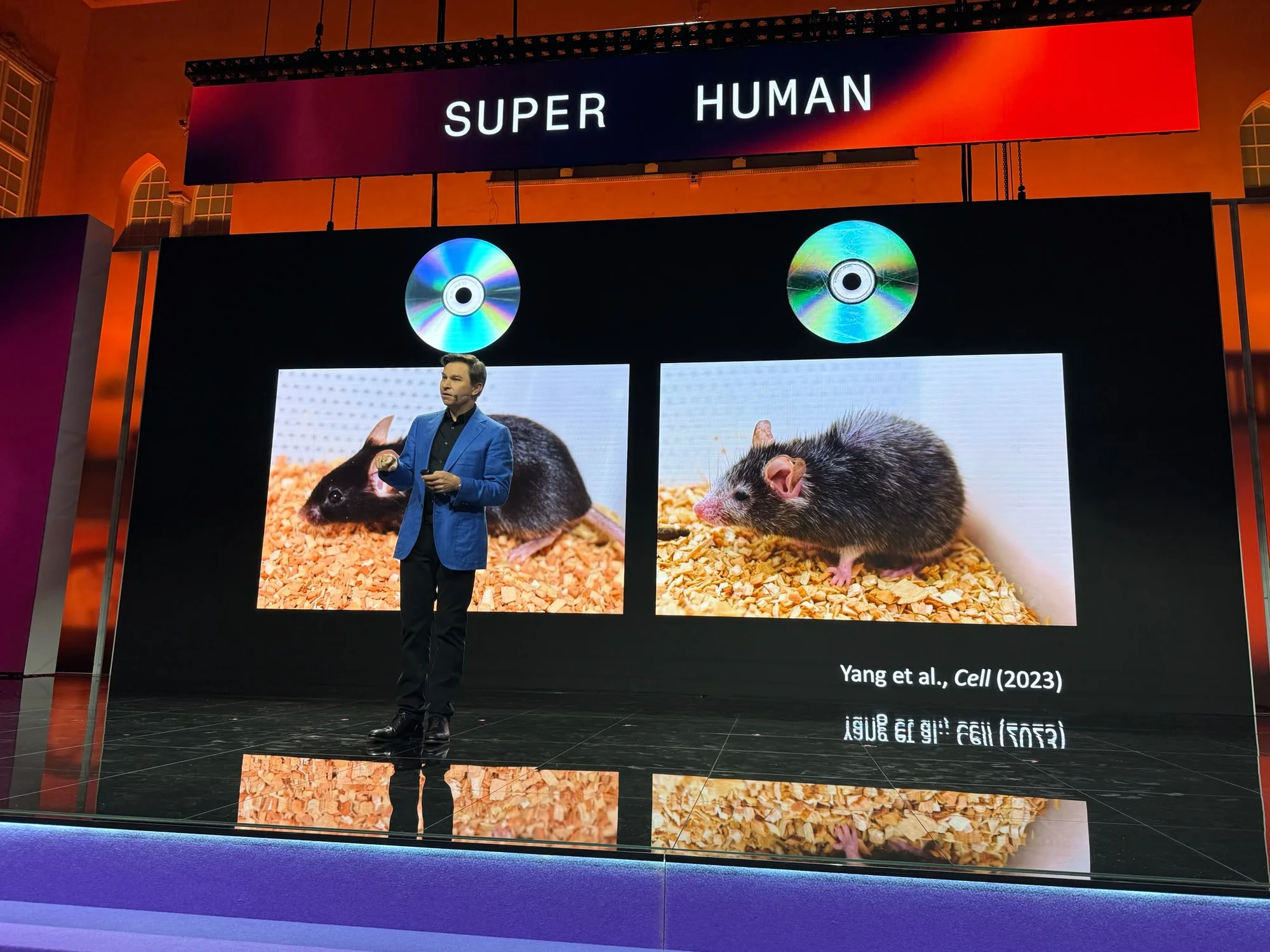 A stage slide showing two mice, one biologically older and one rejuvenated, citing cellular reprogramming research